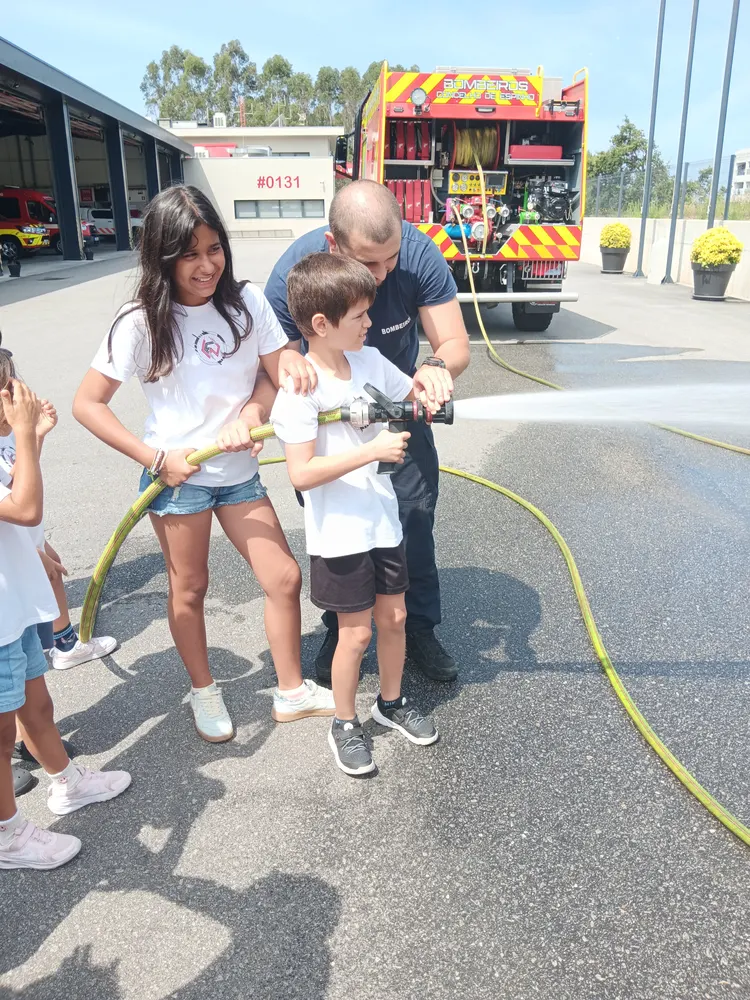 Crianças a manusear a mangueira, na visita aos bombeiros